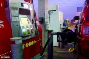 a gas pump fueling up a red car.